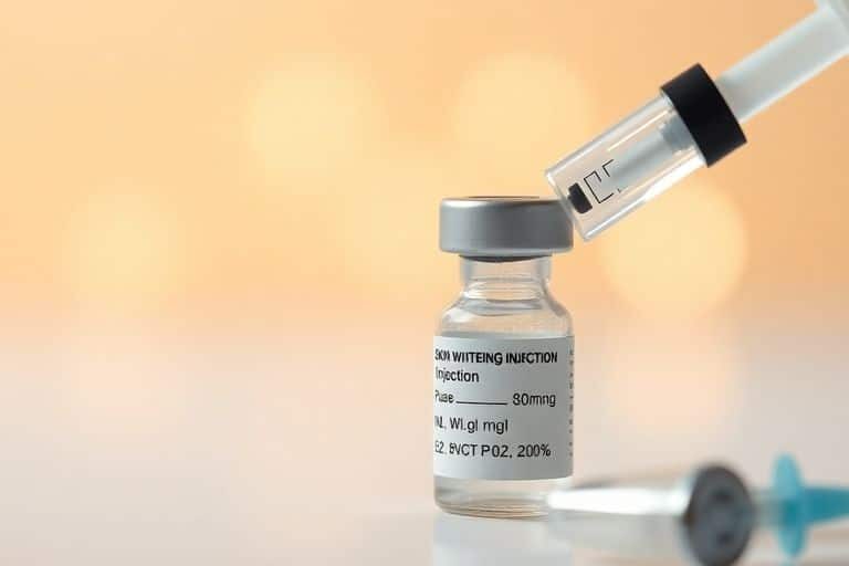 Skin whitening injection preparation with syringe and vials.